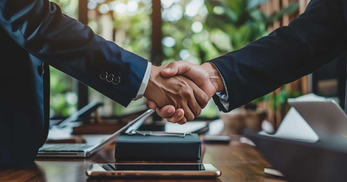 Two business people in suits shaking hands to finalize a deal"