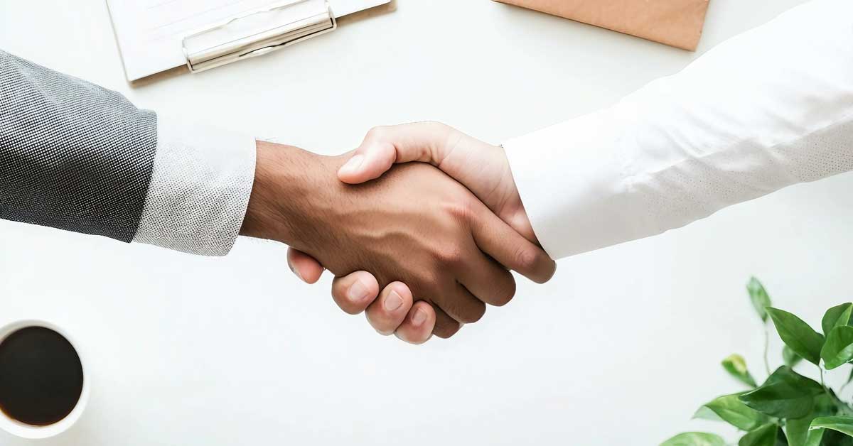 A handshake between two people over a desk, representing partnership and mutual understanding in a business environment.